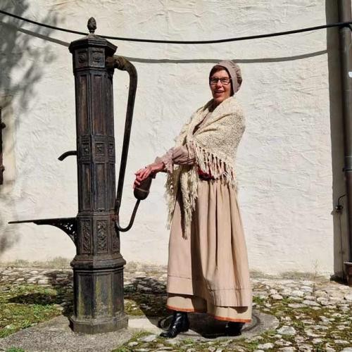 Verkleidete Frau an einer historischen Schwengelpumpe, Foto: Karin Marquard-Mader Verkleidete Frau an einer historischen Schwengelpumpe, Foto: Karin Marquard-Mader
