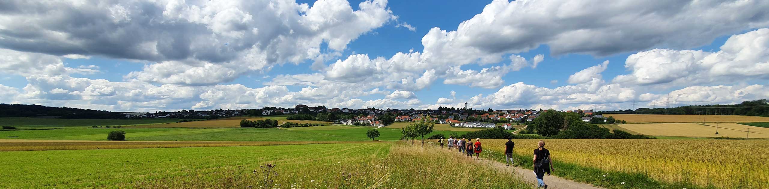 Im Vordergrund eine Bank. Blick auf ein Feld, darüber blauer Himmel mit Wolken, Foto Stadt Heidenhem