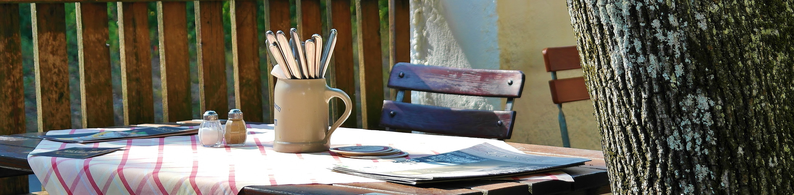 Tisch im Freien mit Bierkrug, Besteck und Zeitung